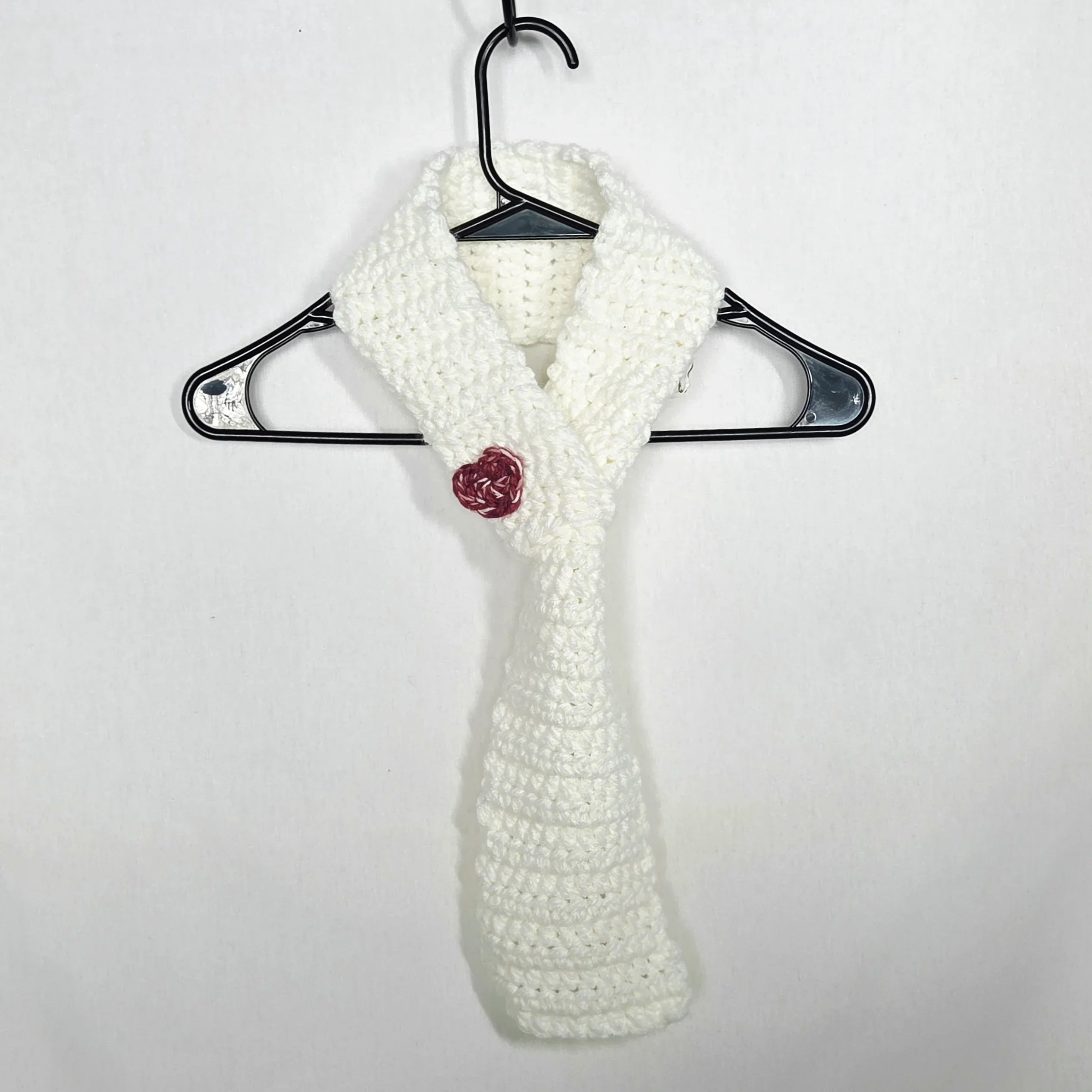 Handmade white crochet scarf with red rose accent on hanger, cozy gift by Erika Liesel