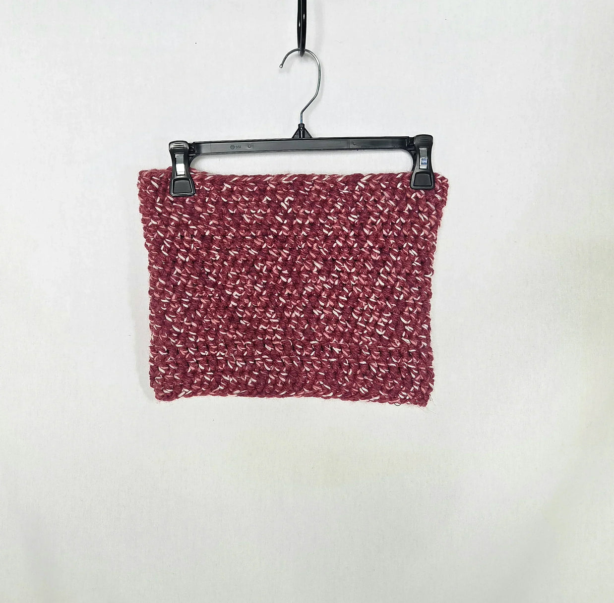 Handmade chunky crochet cowl scarf in maroon, displayed on a hanger against a white background.