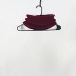 Handmade burgundy crochet scarf draped on black hanger, cozy and textured for everyday comfort