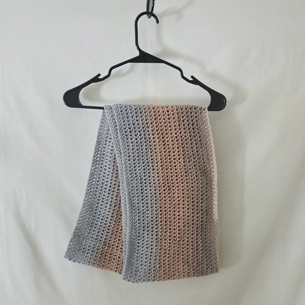 Handmade crochet scarf in soft gray and beige tones on hanger, cozy gift by Erika Liesel