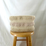 Handmade crochet basket in cream with pink stripe, cozy home decor on wooden stool