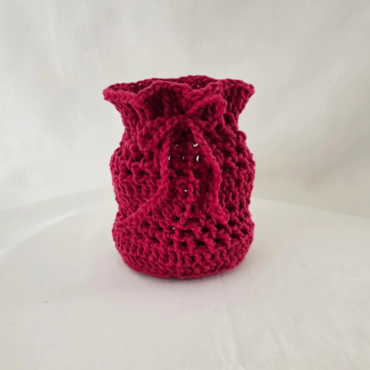 Handmade red crochet drawstring pouch by Erika Liesel on white background