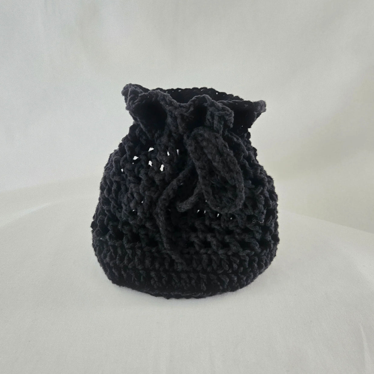 Handmade black crochet drawstring bag by Erika Liesel on white background