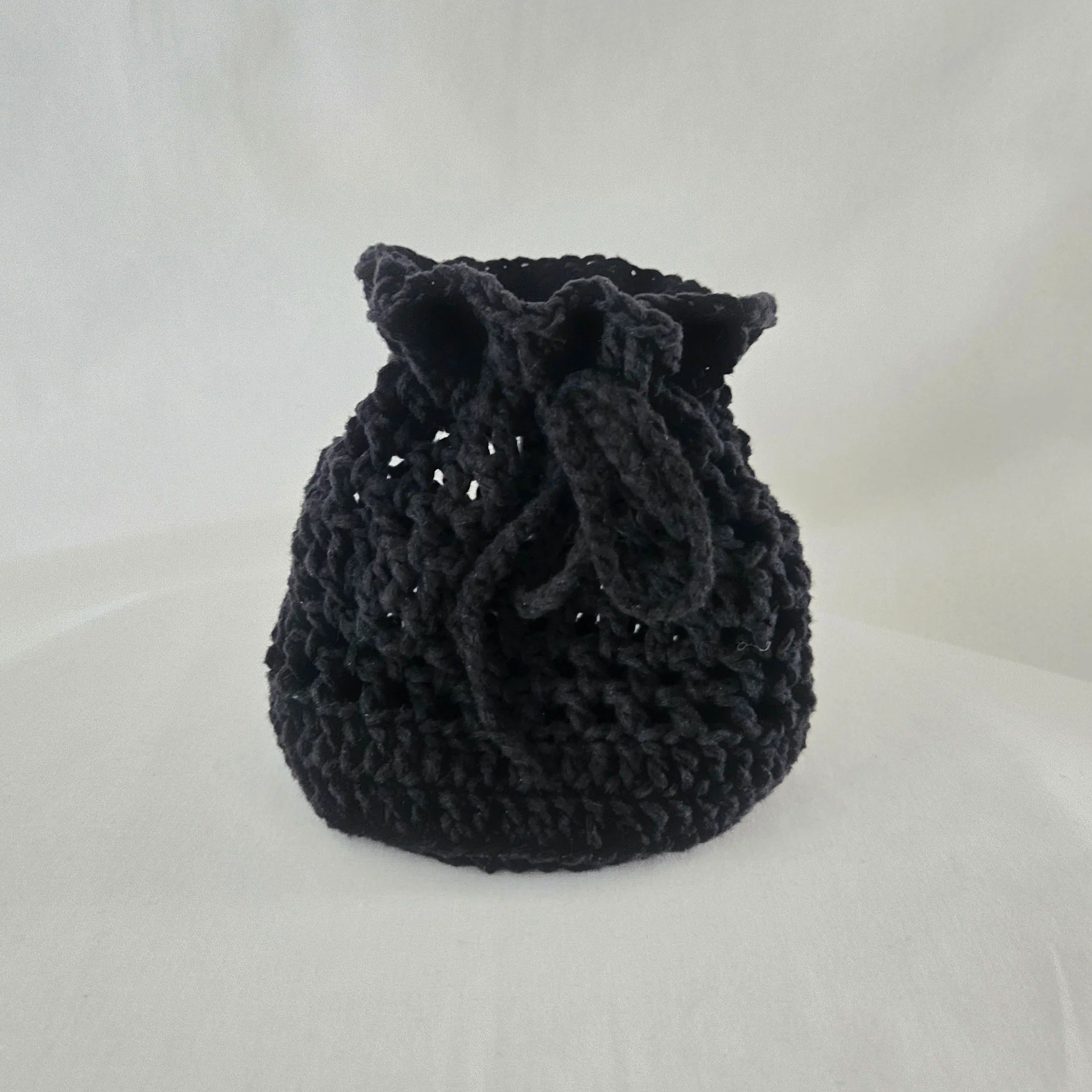 Handmade black crochet drawstring bag by Erika Liesel on white background
