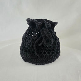 Handmade black crochet drawstring bag by Erika Liesel on white background