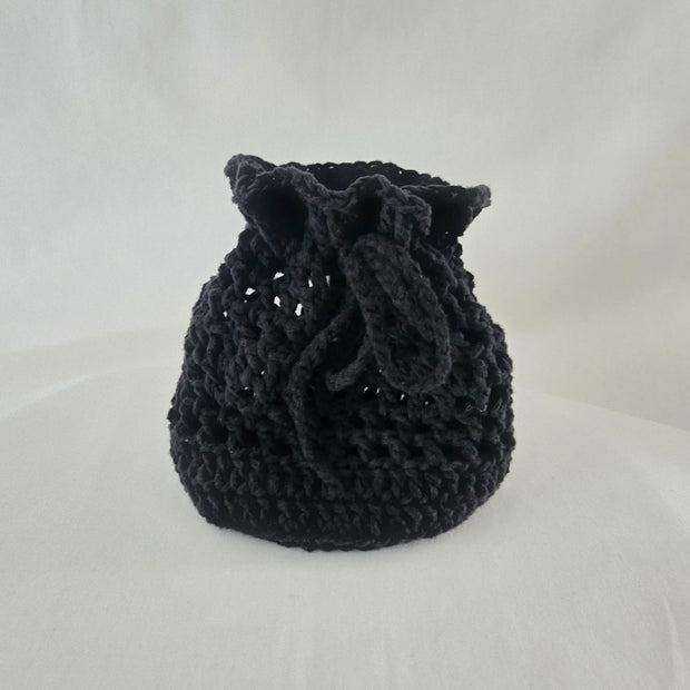 Handmade black crochet drawstring bag by Erika Liesel on white background