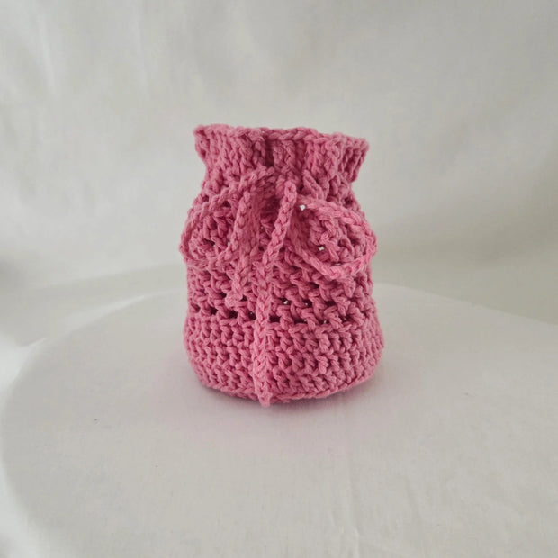 Handmade pink crochet drawstring bag by Erika Liesel on a white background
