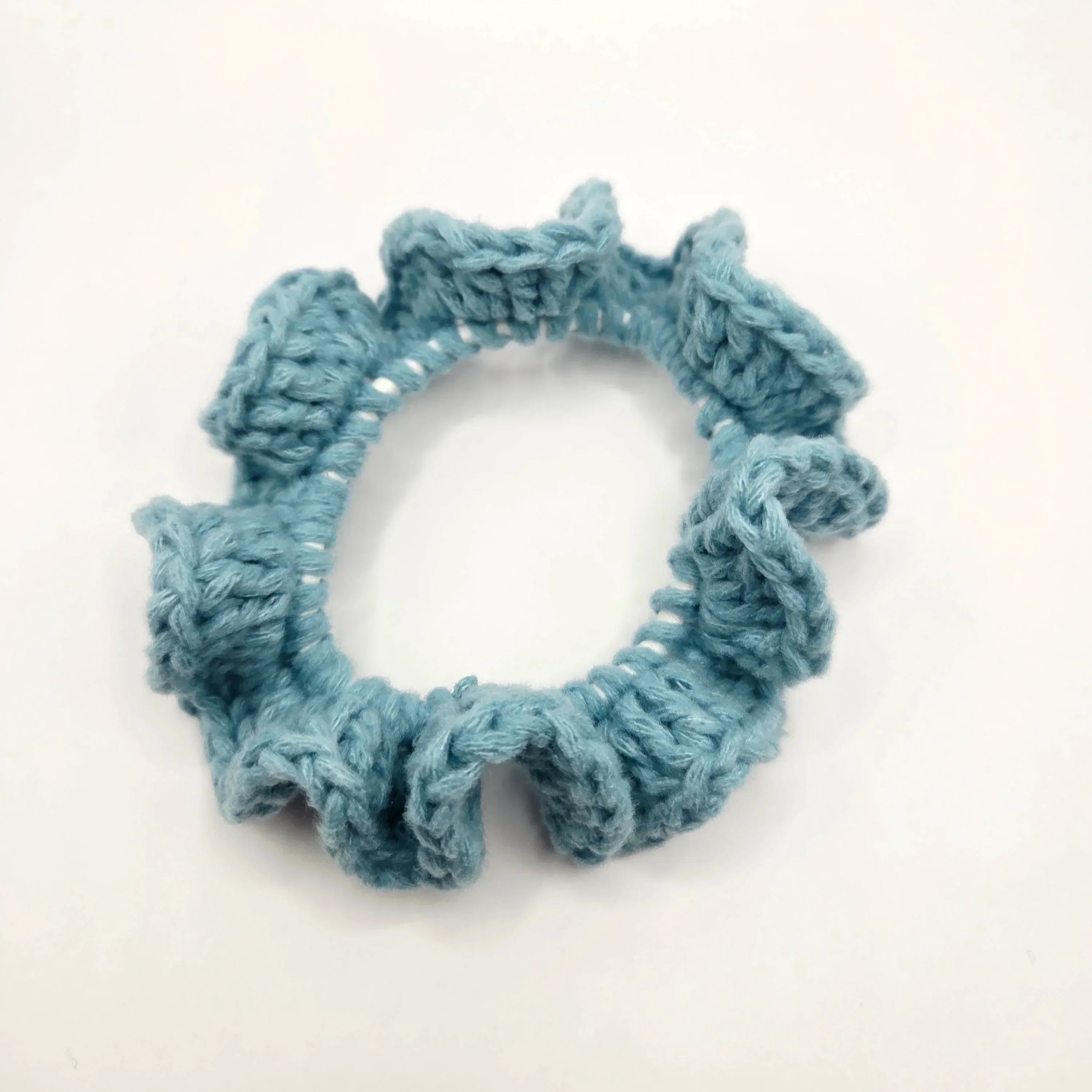 Handmade blue crochet scrunchie on white background, cozy accessory by Erika Liesel