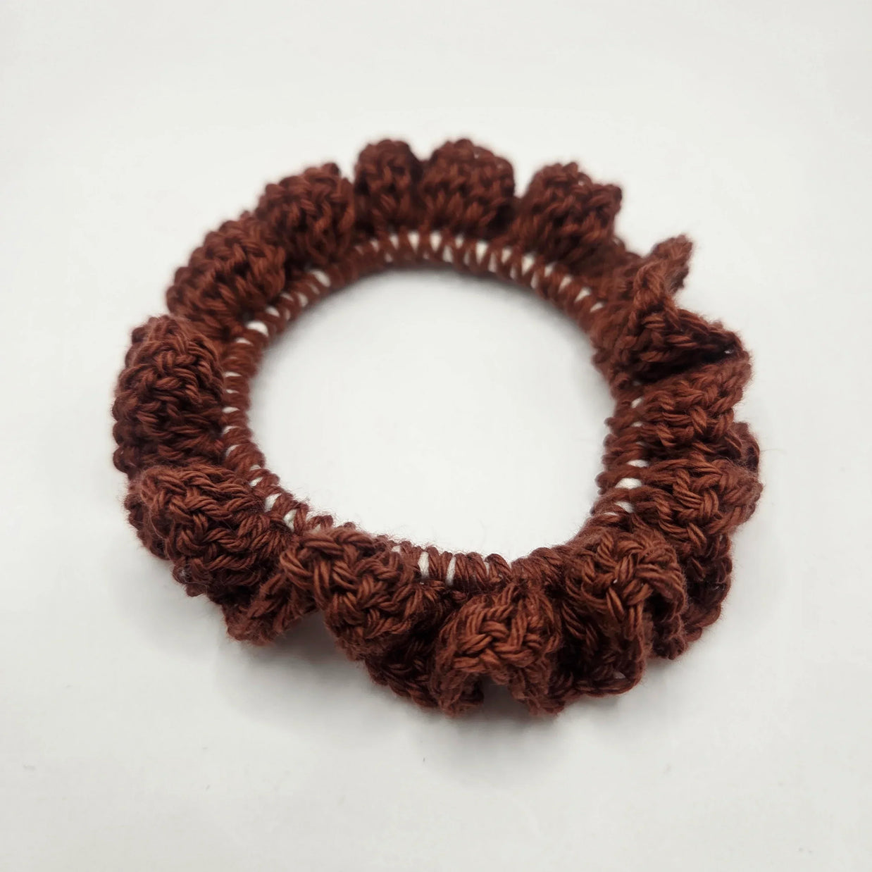 Handmade brown crochet scrunchie on white background, cozy accessory by Erika Liesel