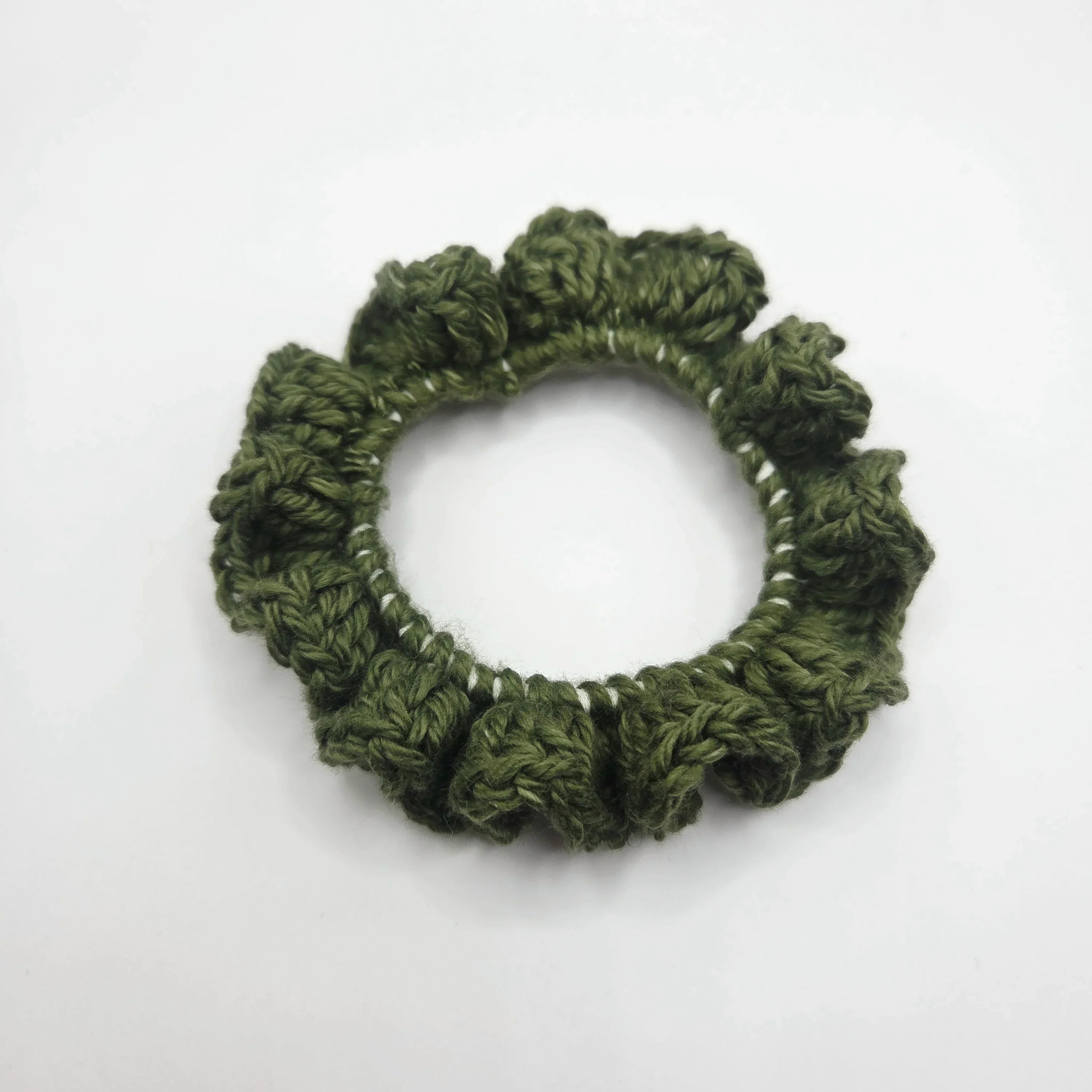 Handmade green crochet scrunchie on white background, cozy accessory by Erika Liesel
