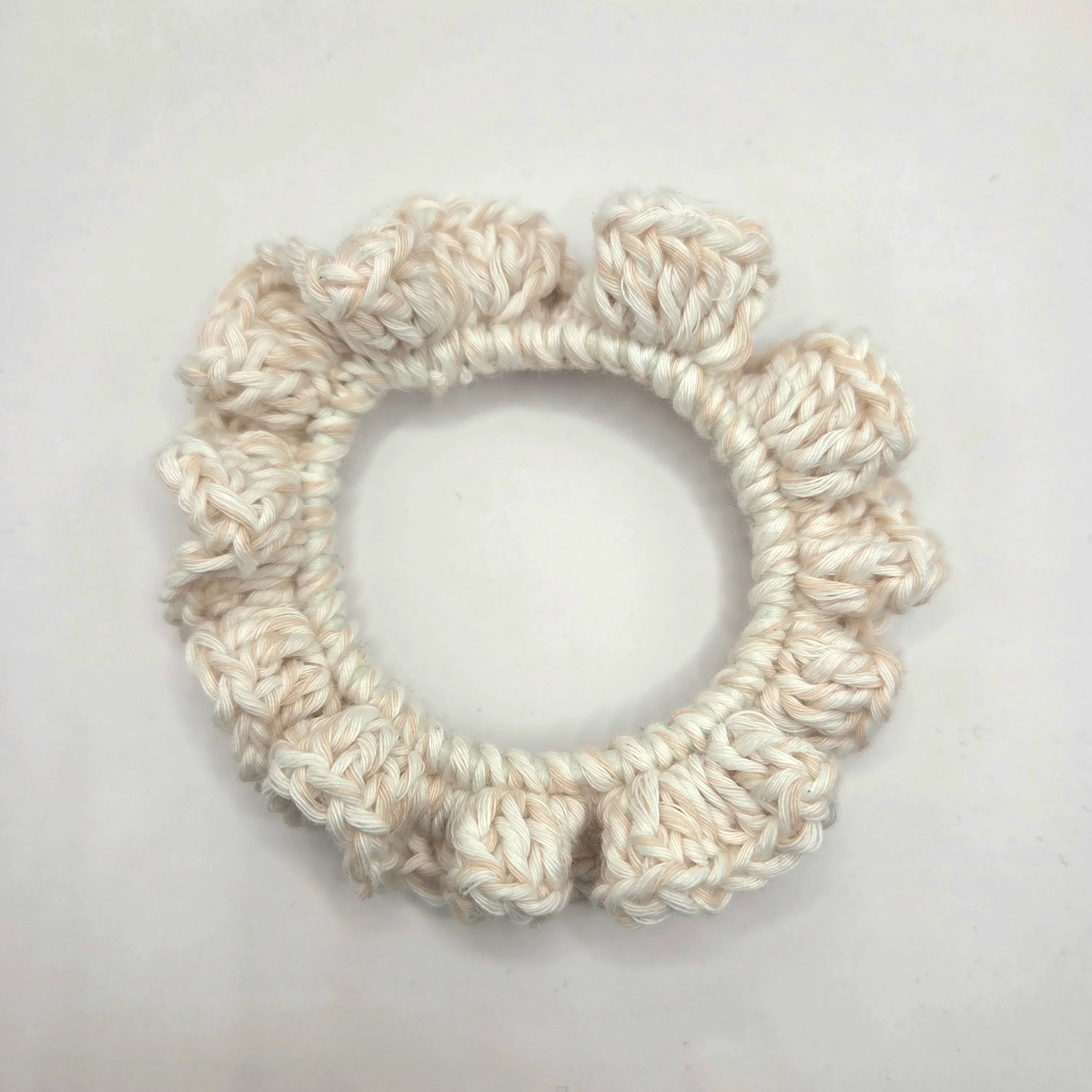 White crochet scrunchie on a light gray background