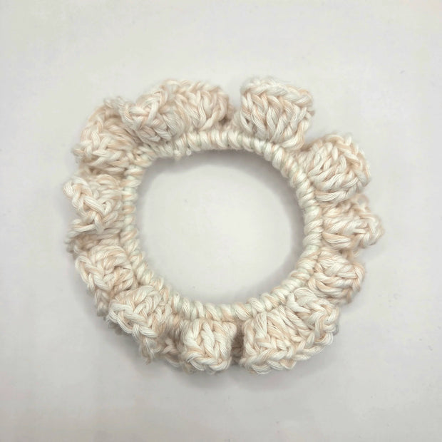 White crochet scrunchie on a light gray background