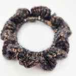 Handmade crochet hair scrunchie in black and brown speckled yarn, cozy and textured for everyday wear.