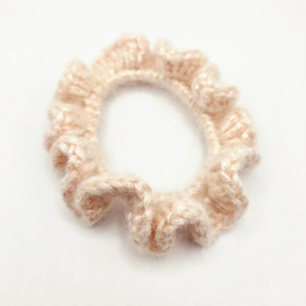 Handmade crochet ruffle scrunchie in soft beige yarn on white background