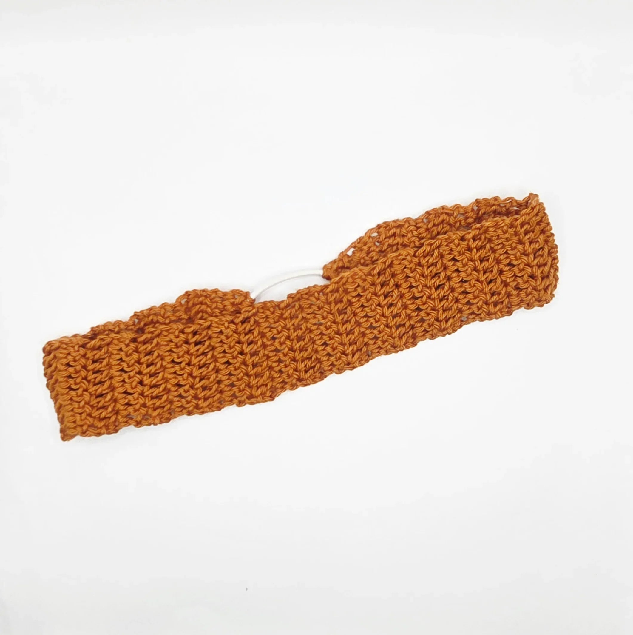 Handmade crochet headband in burnt orange yarn on white background