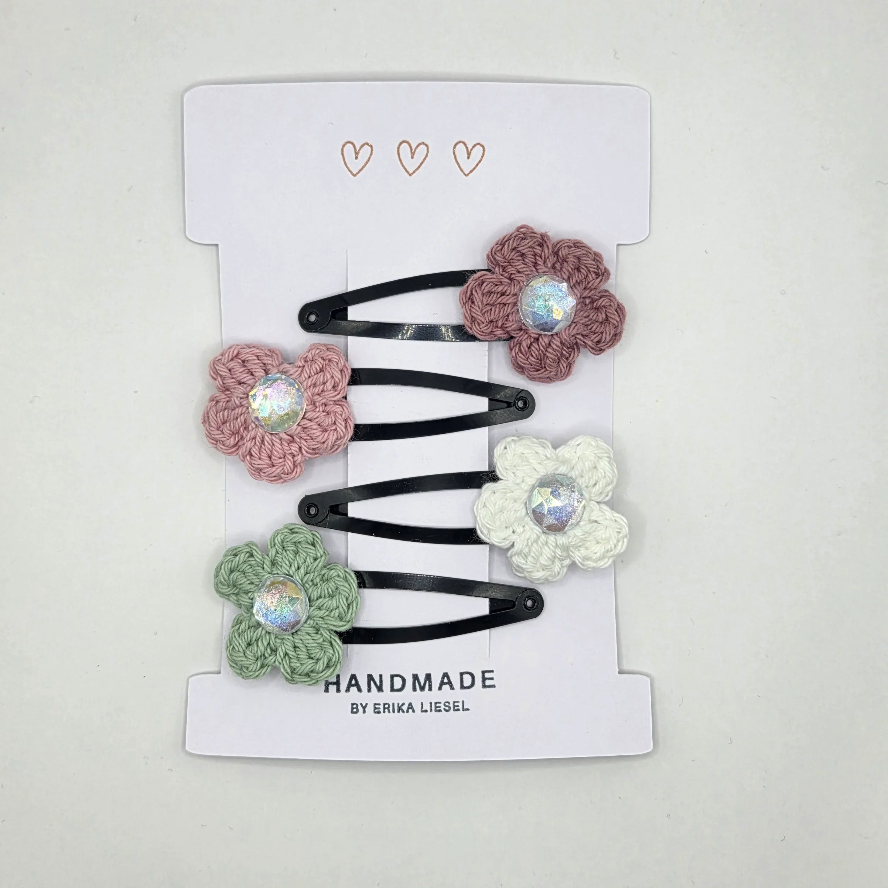 Handmade crochet flower hair clips by Erika Liesel on white card packaging