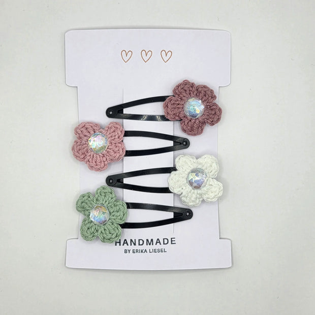 Handmade crochet flower hair clips by Erika Liesel on white card packaging