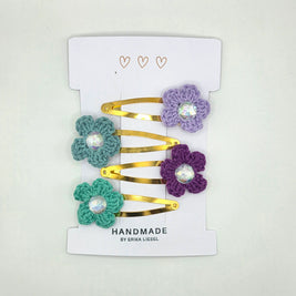 Handmade gold hair clips with crochet flower designs by Erika Liesel on white card.