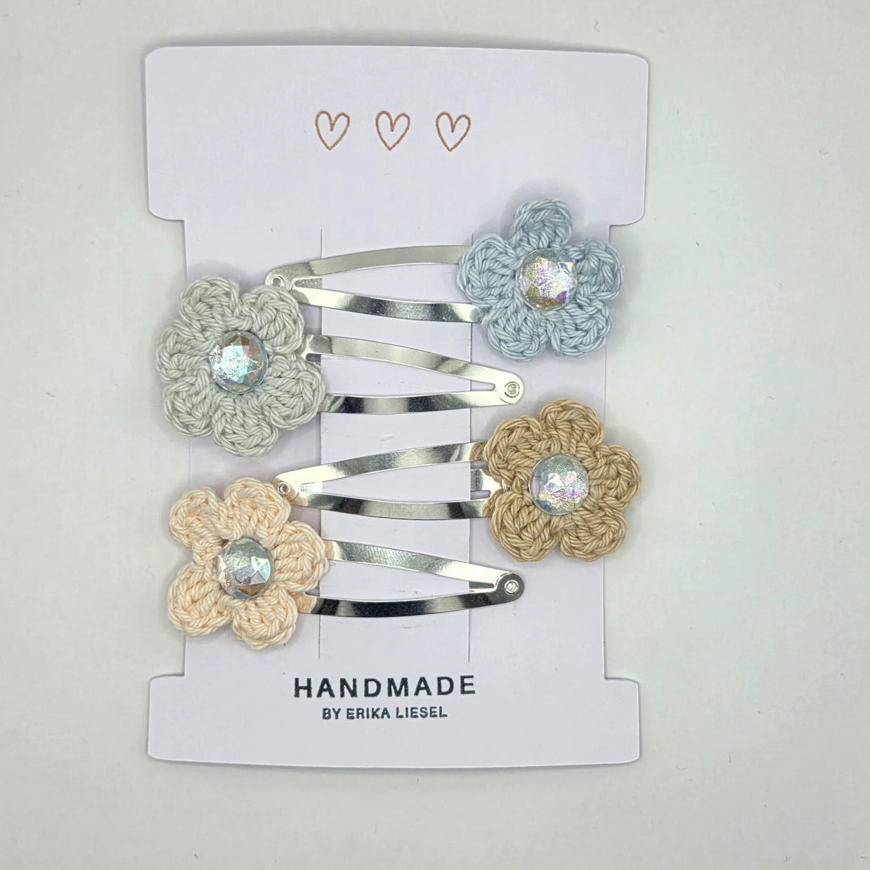 Handmade crochet flower hair clips by Erika Liesel on white card display