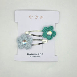 Handmade crochet flower hair clips by Erika Liesel on white card with heart accents