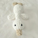 Handmade crochet duck toy with white body, tan beak, and black eyes on soft fabric background