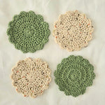 Handmade crochet coasters in sage green and speckled cream, featuring floral scalloped edges for cozy home decor.