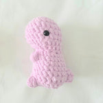 Handmade pink crochet dinosaur toy with black button eye, cozy amigurumi gift for kids