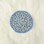 Handmade crochet coaster in blue and cream, featuring a circular pattern for cozy home decor.