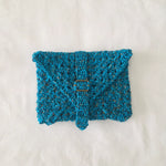 Handmade crochet clutch in vibrant blue with gold buckle, cozy and creative accessory
