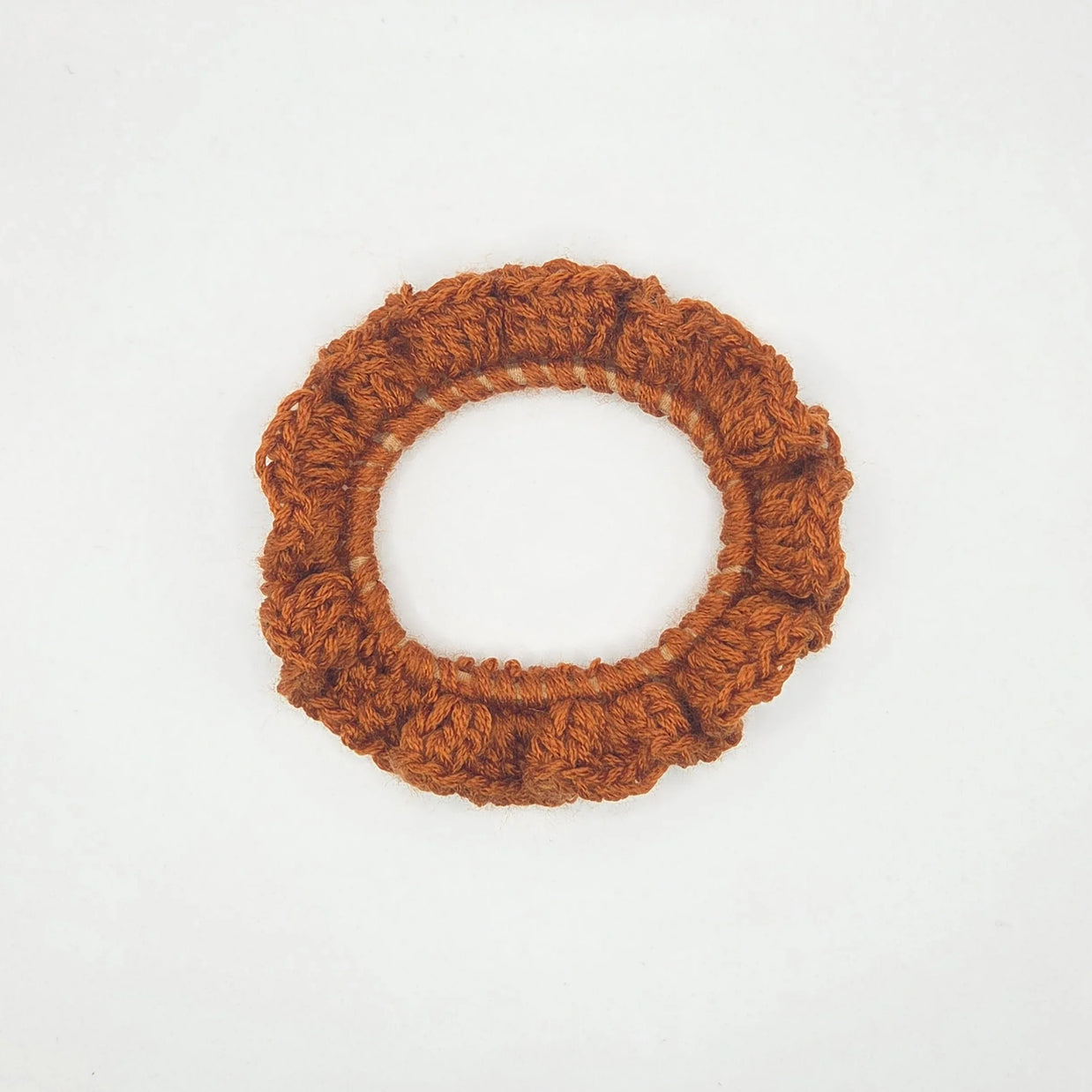 Handmade brown crochet scrunchie on white background, cozy hair accessory by Erika Liesel