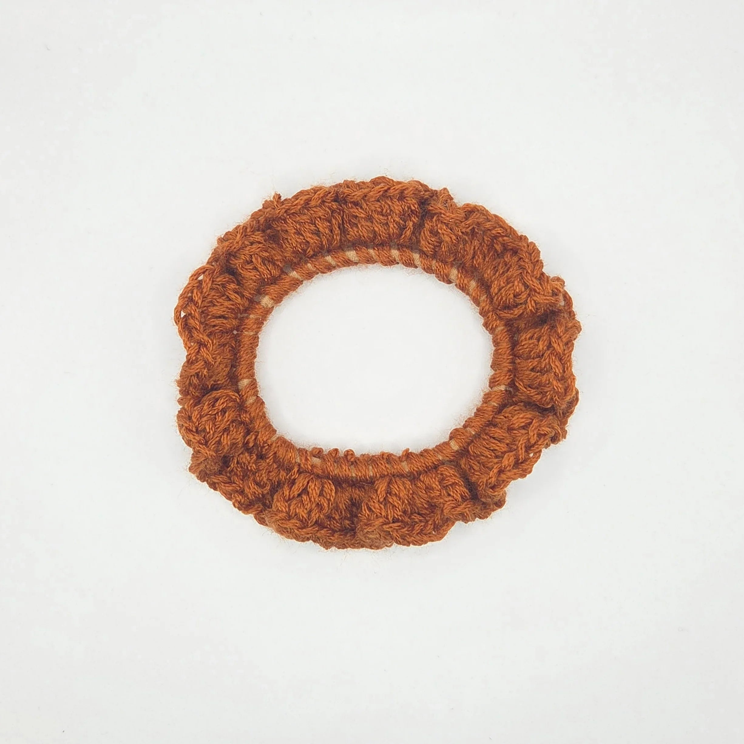 Handmade brown crochet scrunchie on white background, cozy hair accessory by Erika Liesel