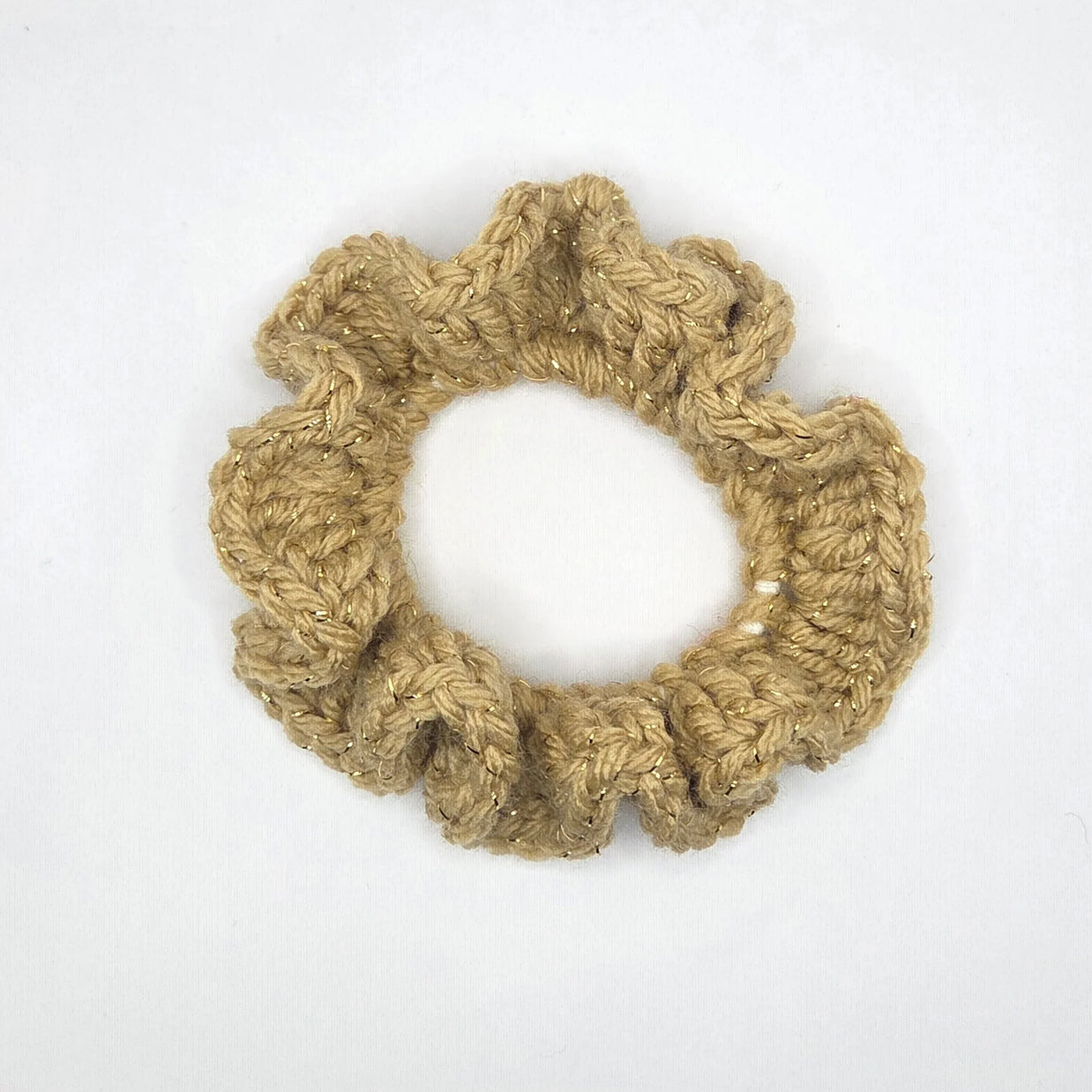 Handmade crochet scrunchie in beige yarn with gold accents on white background