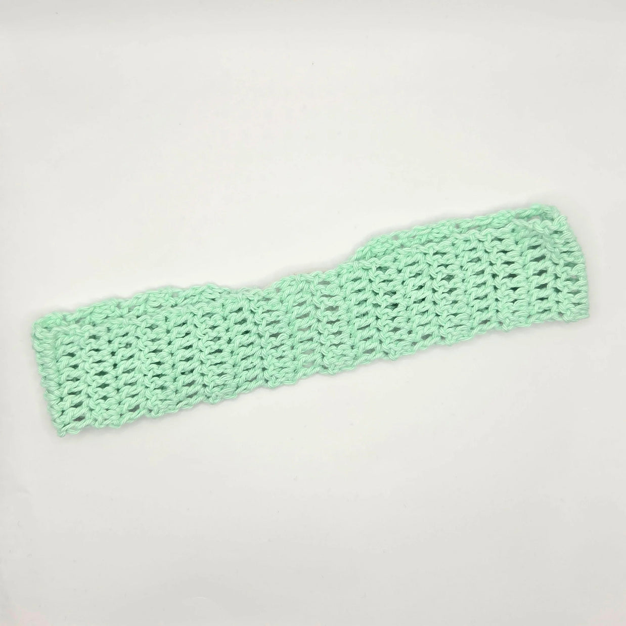 Handmade mint green crochet headband on white background, cozy crochet accessory gift