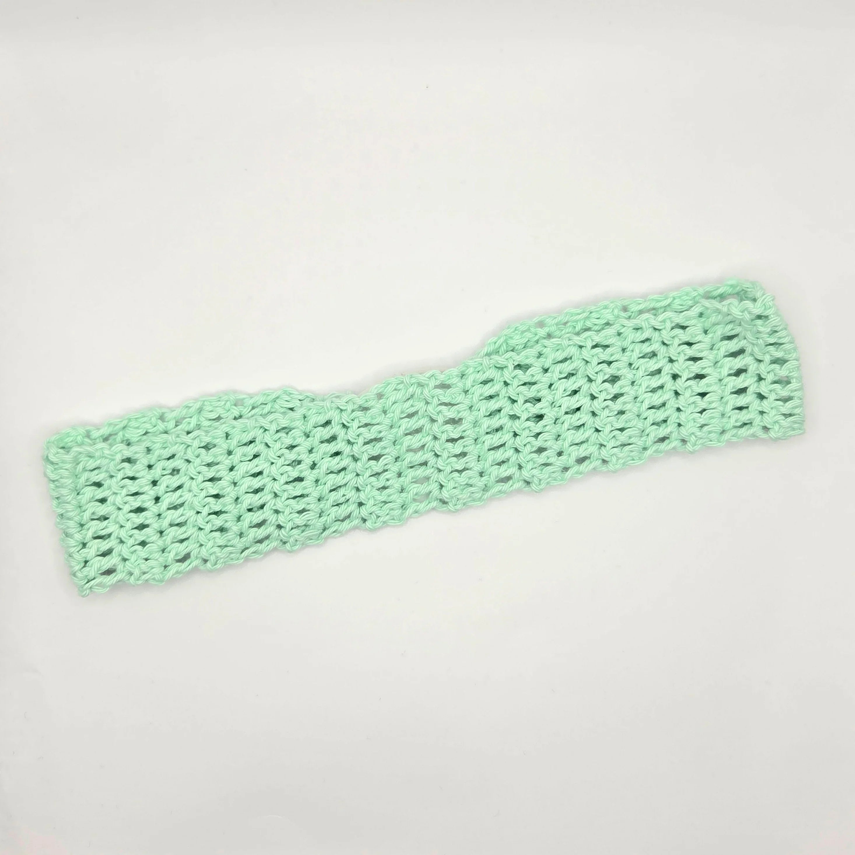 Handmade mint green crochet headband on white background, cozy crochet accessory gift