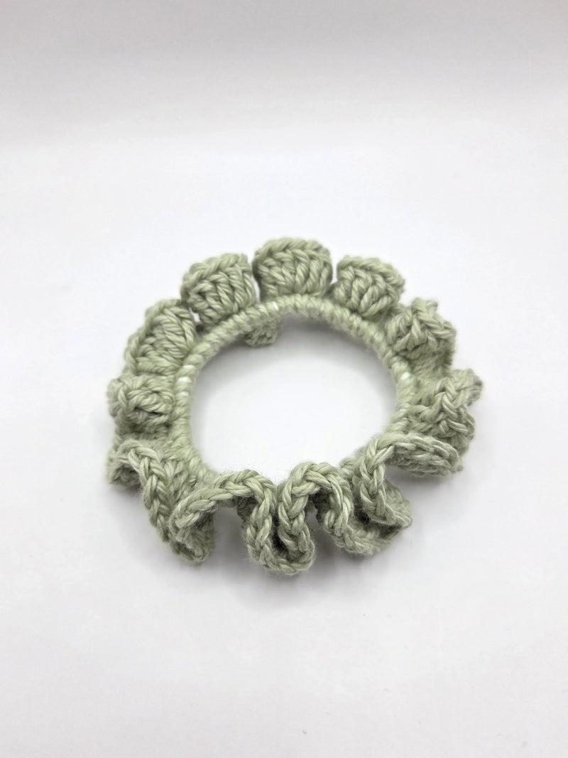 Handmade crochet scrunchie in soft sage green, cozy and textured for everyday wear