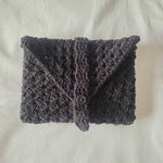 Handmade crochet clutch in dark gray with button closure, cozy and textured for everyday use.