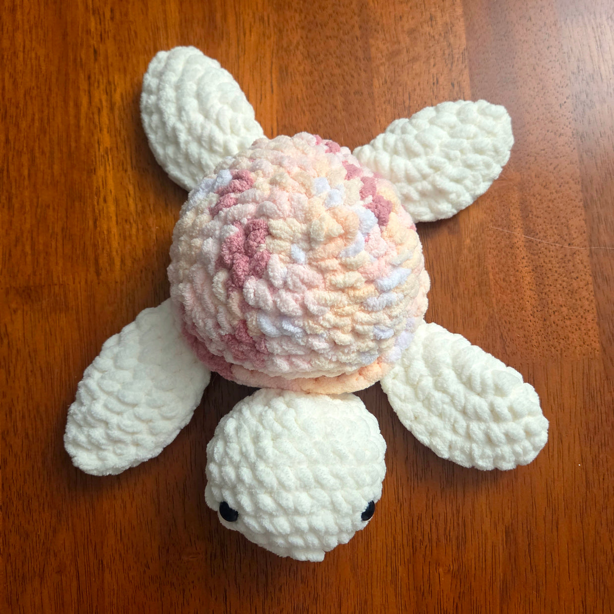 Handmade crochet turtle with pastel shell, cozy and creative amigurumi design on wooden surface