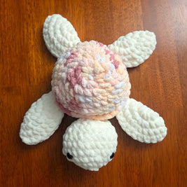 Handmade crochet turtle with pastel shell, cozy and creative amigurumi design on wooden surface