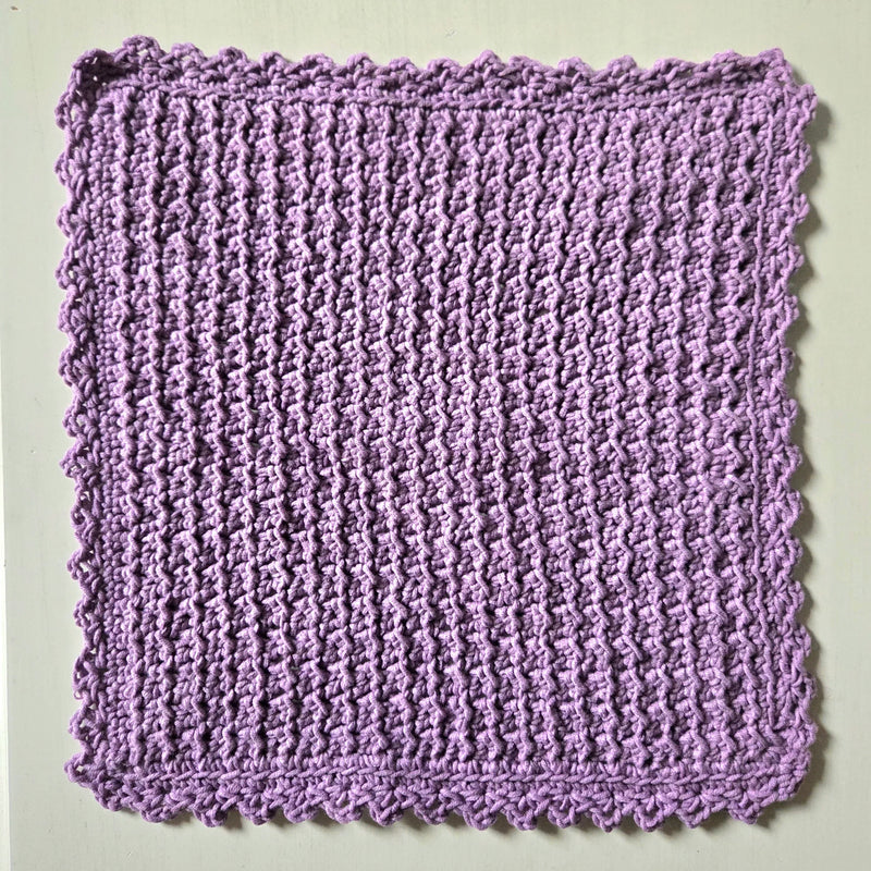 Handmade lavender crochet dishcloth with scalloped edges, perfect for cozy kitchen decor