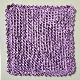 Handmade lavender crochet dishcloth with scalloped edges, perfect for cozy kitchen decor
