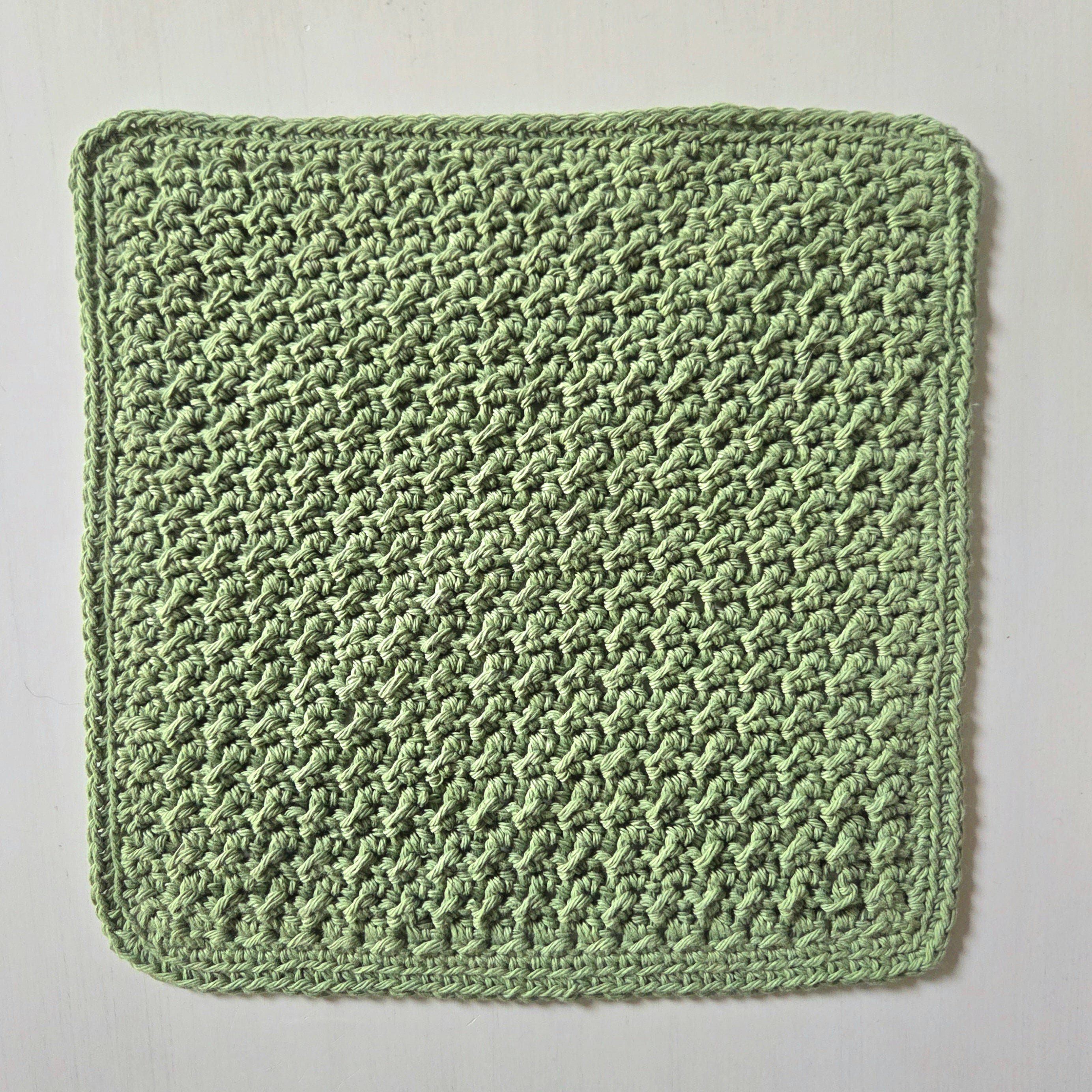 Handmade green crochet dishcloth with textured pattern for cozy kitchen use