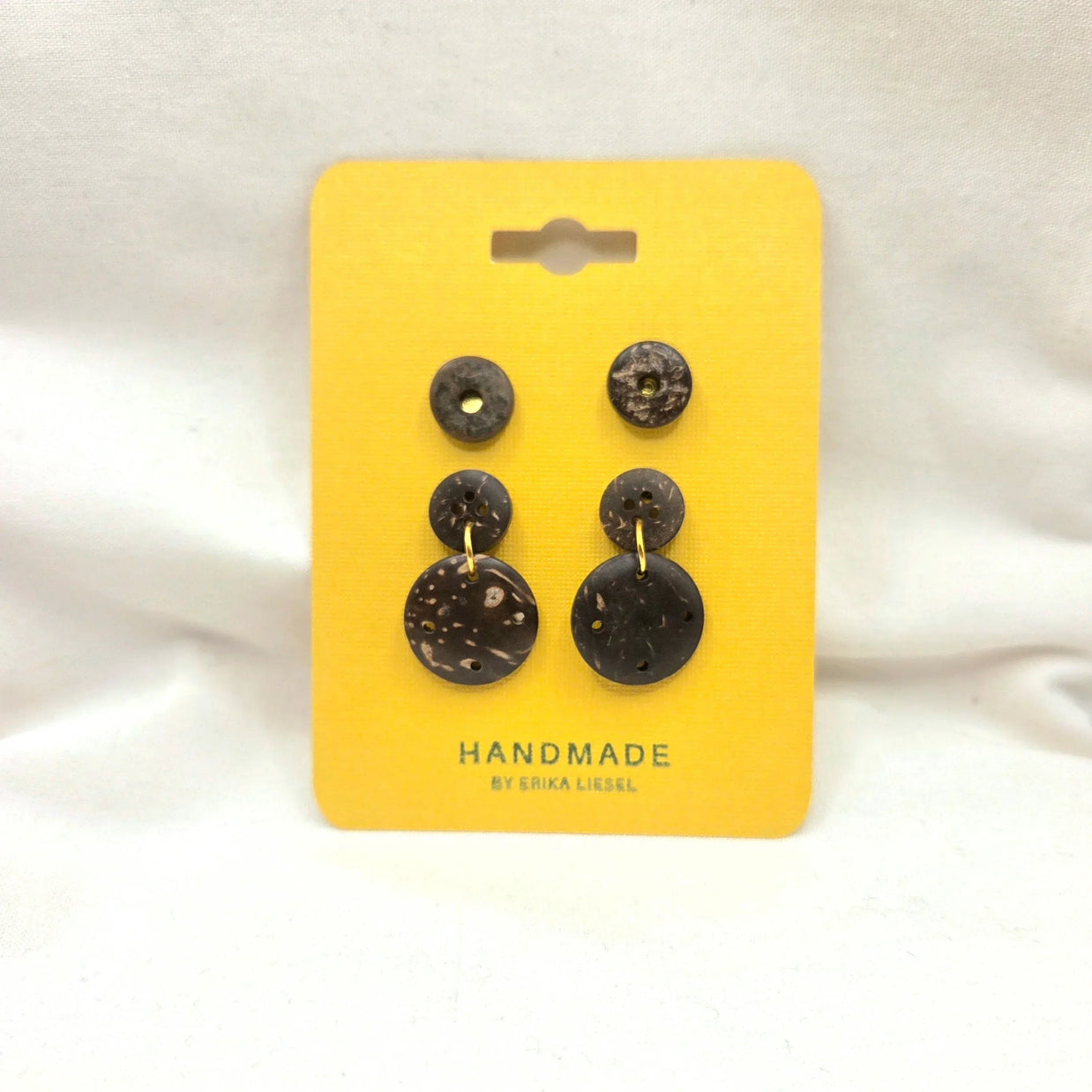 Handmade coconut shell button earrings on yellow card, natural texture, gold accents, artisan crafted