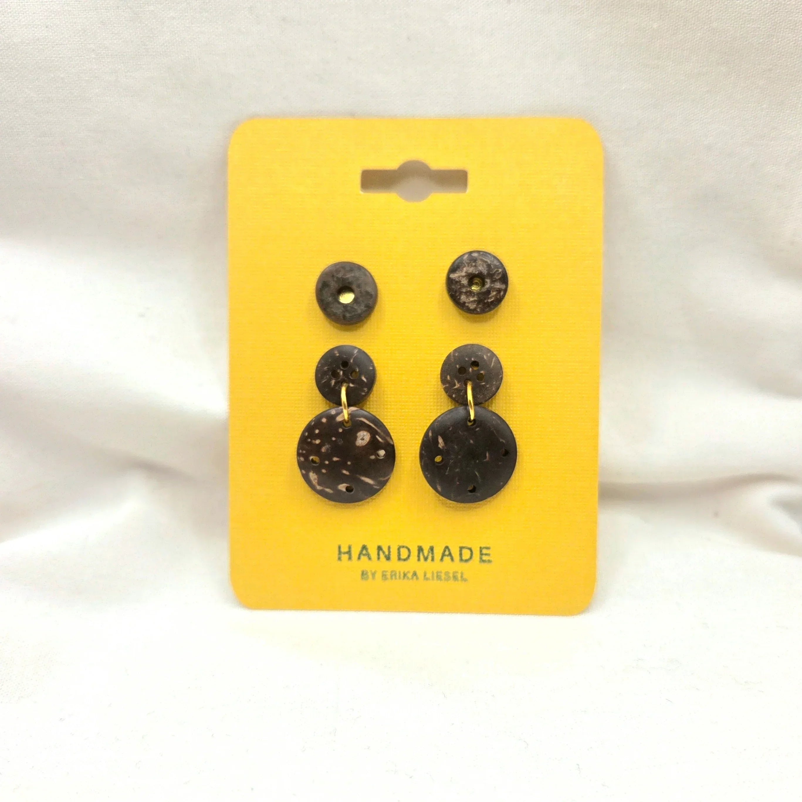 Handmade coconut shell button earrings on yellow card, natural texture, gold accents, artisan crafted