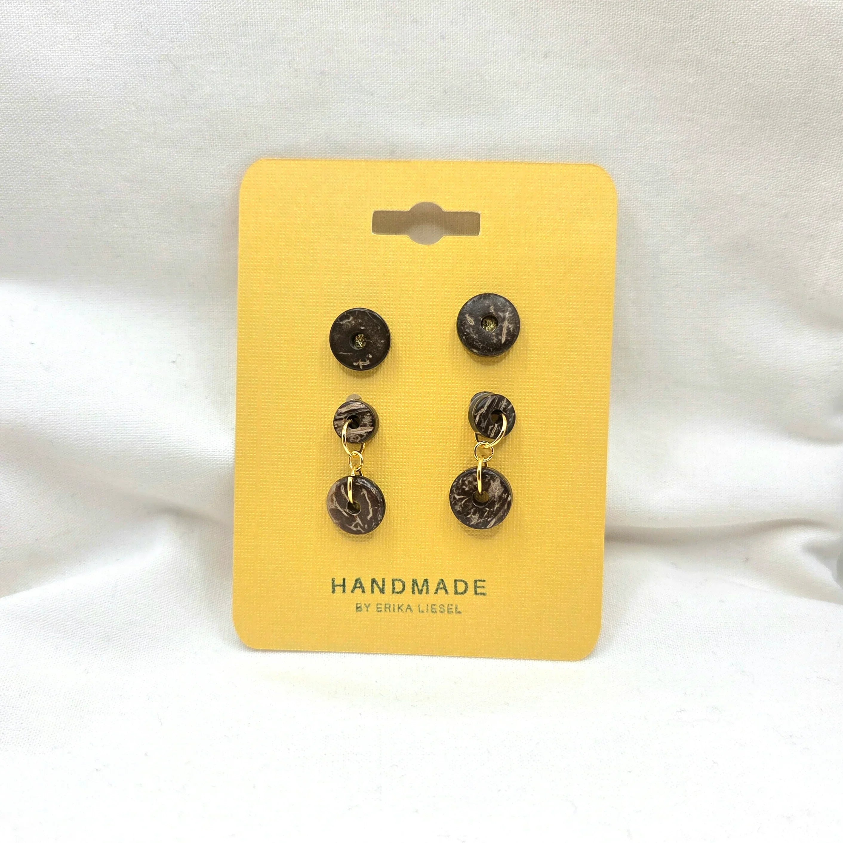 Handmade coconut shell dangle earrings with gold accents on yellow display card