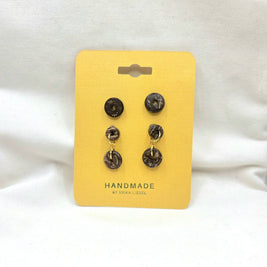 Handmade coconut shell dangle earrings with gold accents on yellow display card