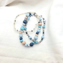 Handmade beaded necklace with blue, gray, and peach beads on cream cord, cozy artisan jewelry