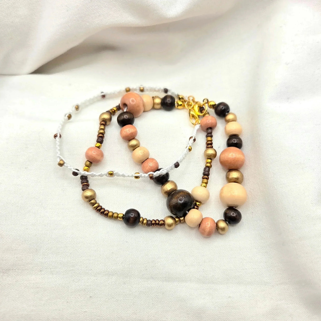 Handmade beaded necklace with peach, gold, and dark wood beads on white cord, cozy artisan jewelry