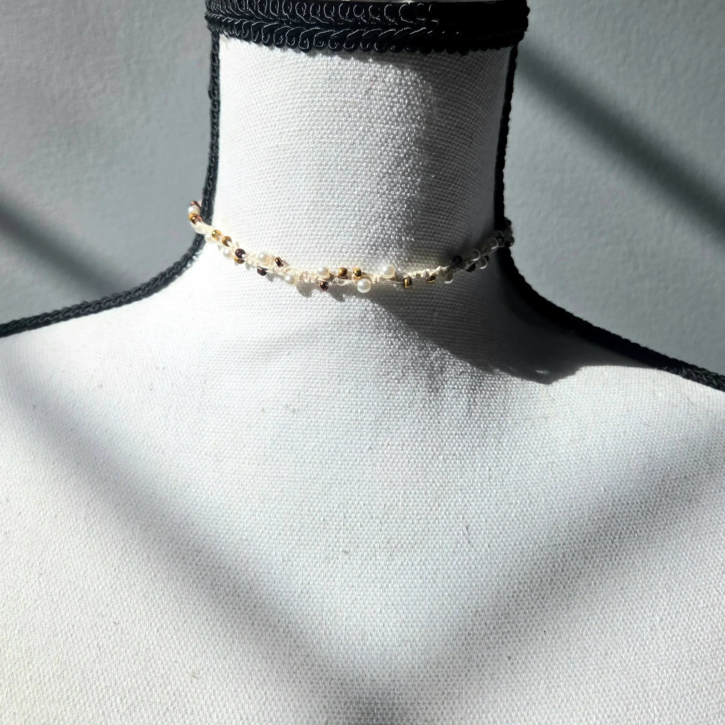 Handmade beaded choker necklace with pearls and gold beads, displayed on mannequin