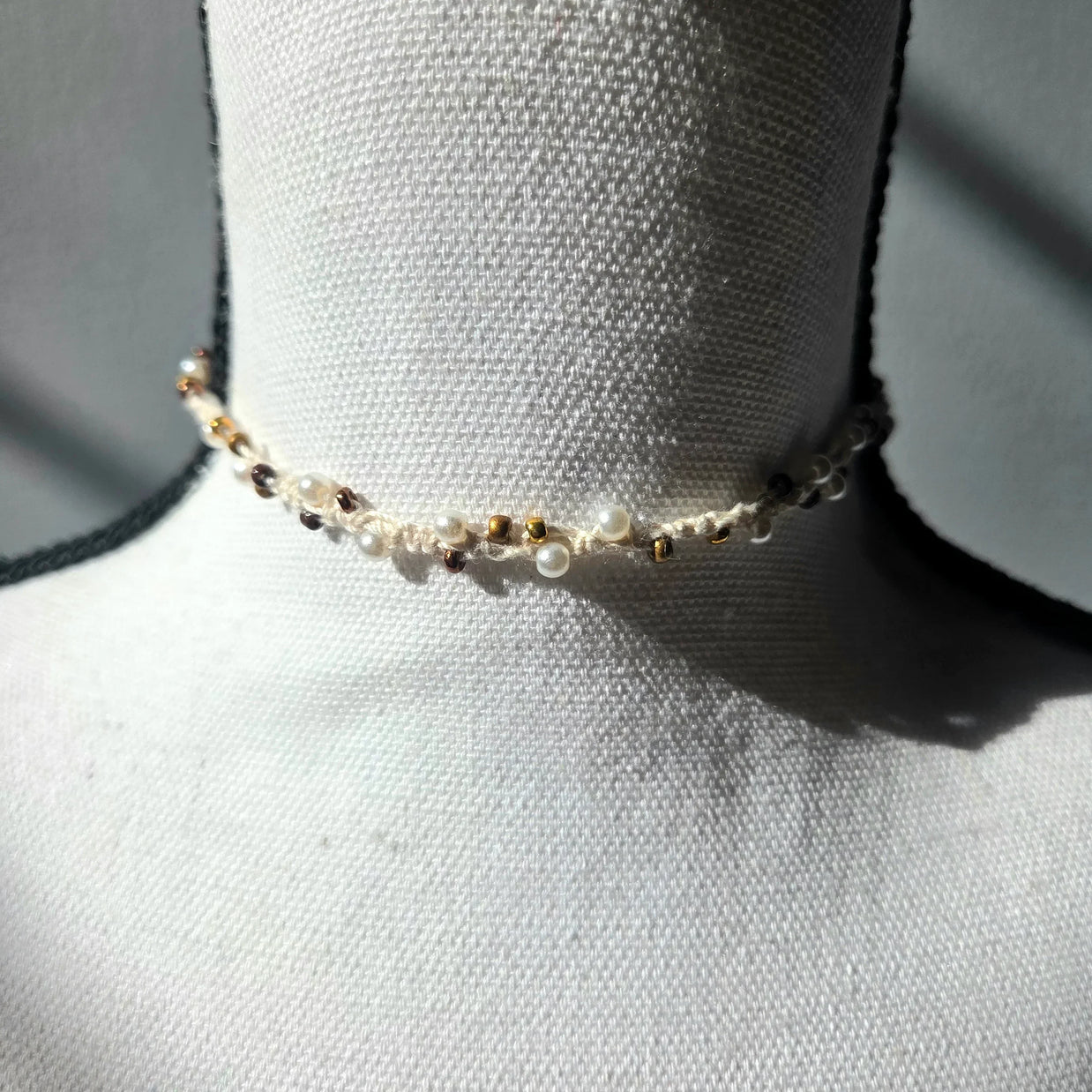 Delicate handmade pearl and gold bead choker necklace on white mannequin, cozy crochet gift