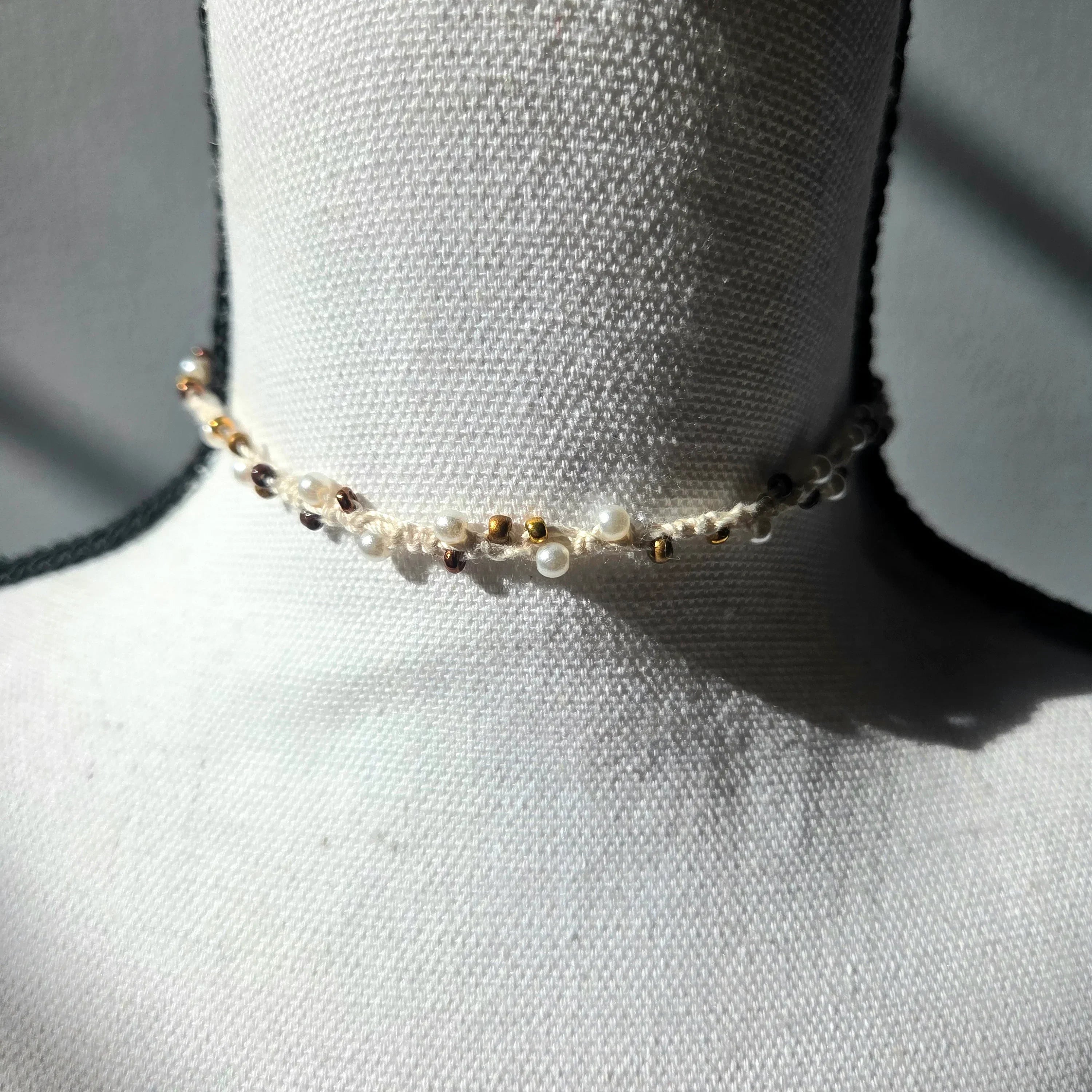 Delicate handmade pearl and gold bead choker necklace on white mannequin, cozy crochet gift